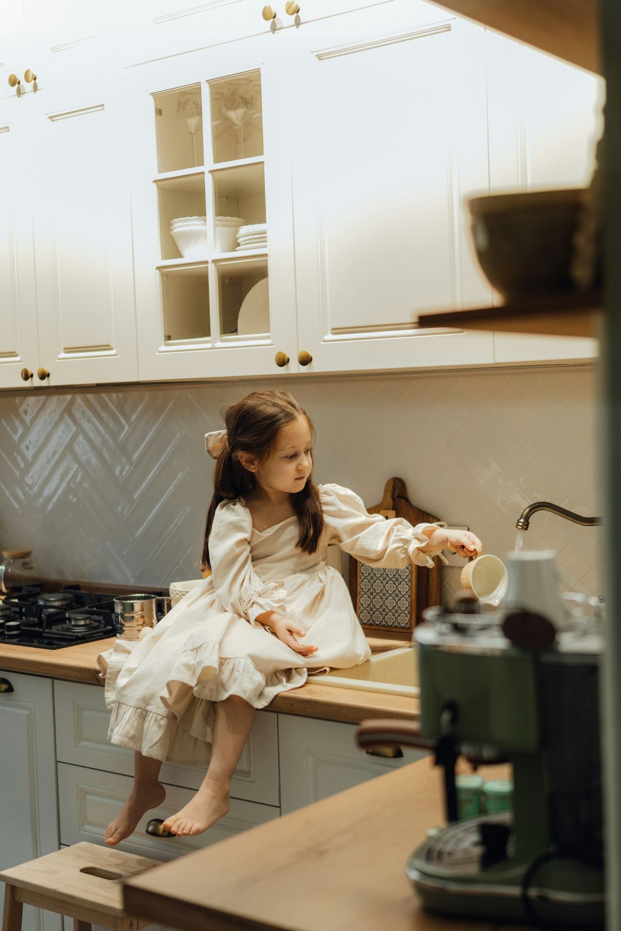 A little girl sitting on a counter in a kitchen